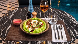 A dining table with a salad, a bottle, a glass of wine, and cutlery. - Bab Hotel (Marrakech)