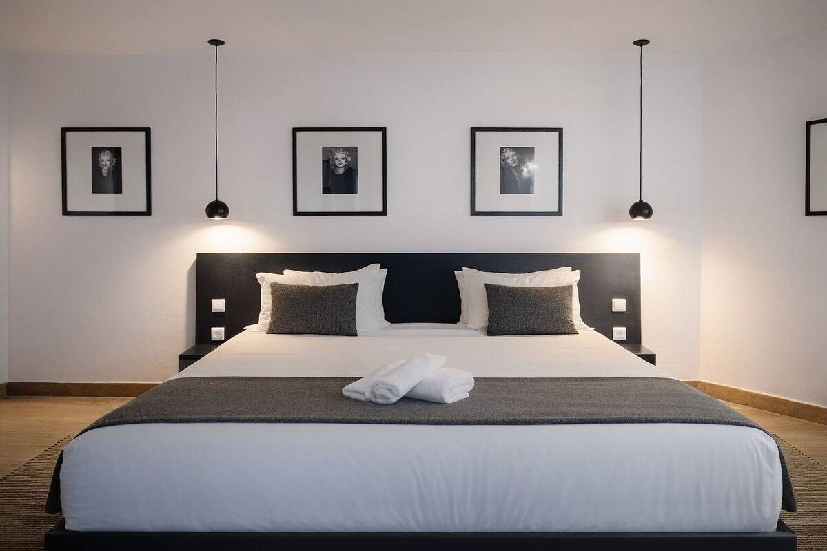 A hotel room with a large bed, a headboard, and three framed pictures on the wall.
