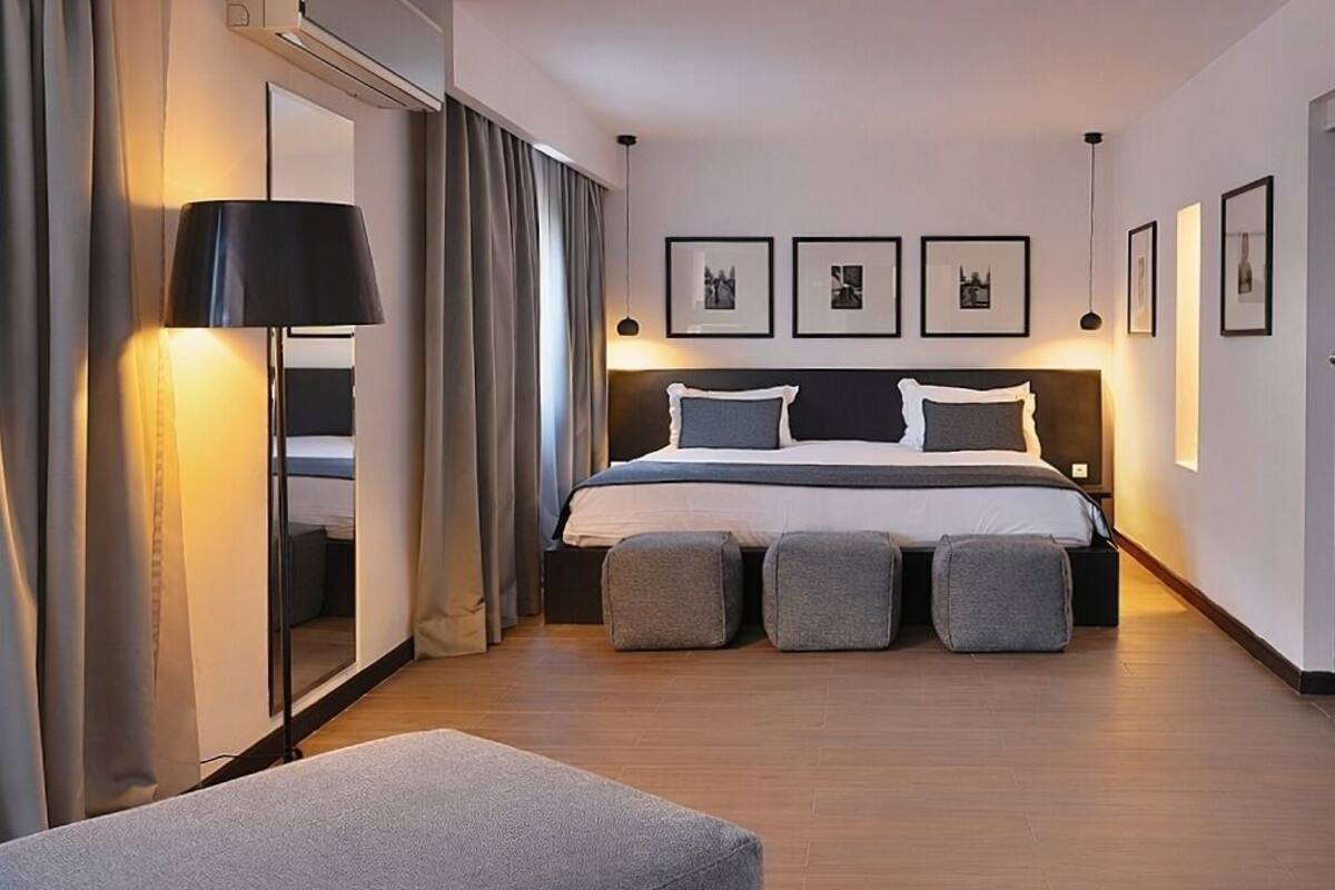 A modern hotel room with a large bed, bedside lamps, a mirror, and framed pictures on the wall.