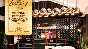 A hotel lobby with a large reception desk, a modern chandelier, and a 'Luxury Lifestyle Awards Winner' plaque. - Bab Hotel (Marrakech)