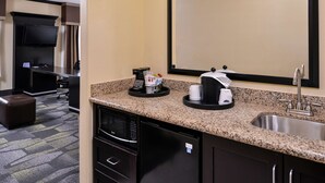 A hotel room with a kitchenette, including a microwave, refrigerator, sink, and a flat-screen TV mounted on the wall. - Hampton Inn & Suites Big Spring (Big Spring)