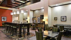A hotel lobby with a central seating area, multiple tables, and chairs, a patterned rug, and wall-mounted artwork. - Hampton Inn & Suites Big Spring (Big Spring)