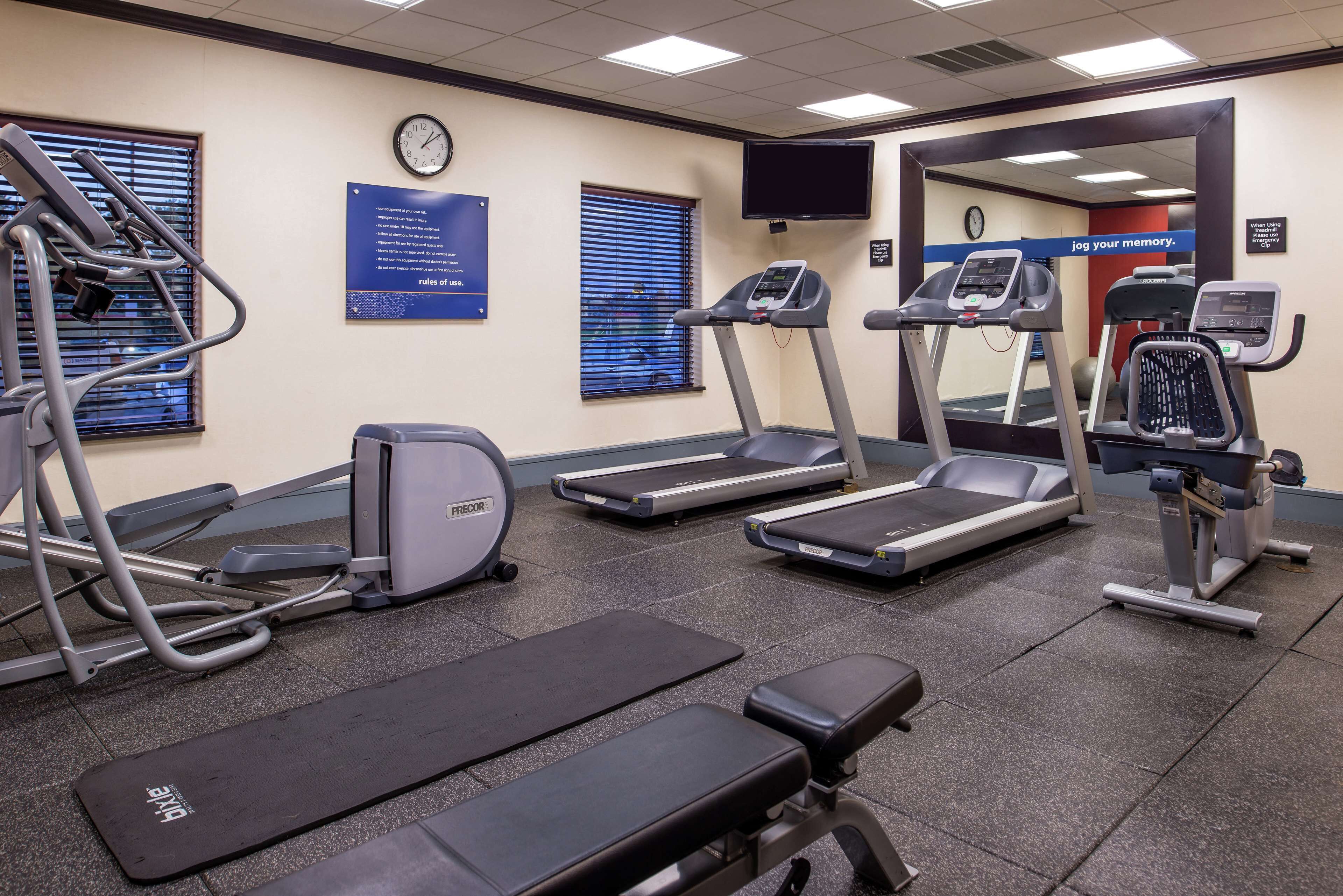 Une salle de sport équipée de tapis de course, d’un appareil elliptique et d’un banc de musculation.