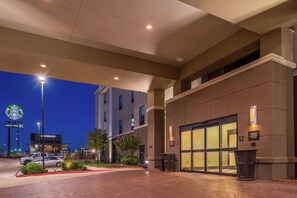 A hotel entrance with a Starbucks drive-thru, a parking lot, and a building with a glass facade. - Hampton Inn & Suites Big Spring (Big Spring)