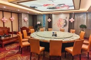 Un salón de conferencias con una mesa redonda, sillas y una pantalla grande.