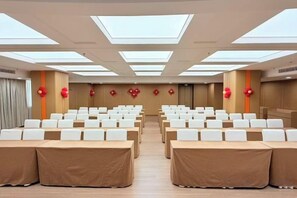 A conference room with rows of tables and chairs, large windows, and red decorative elements. - Dihao Hotel (Quanzhou)