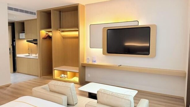 A modern hotel room with a sofa, a TV mounted on the wall, and a walk-in closet. - Dihao Hotel (Quanzhou)