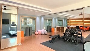 A modern gym with exercise equipment, a treadmill, and a mirrored wall. - Dihao Hotel (Quanzhou)