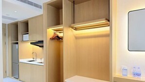 A modern kitchen with built-in appliances, a countertop sink, and a shelf with shoes and water bottles. - Dihao Hotel (Quanzhou)