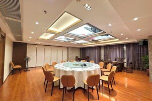 Un salón de conferencias con una mesa redonda, sillas y un techo con tragaluces.