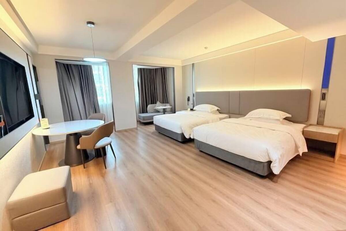 A hotel room with two beds, a desk, and a chair.