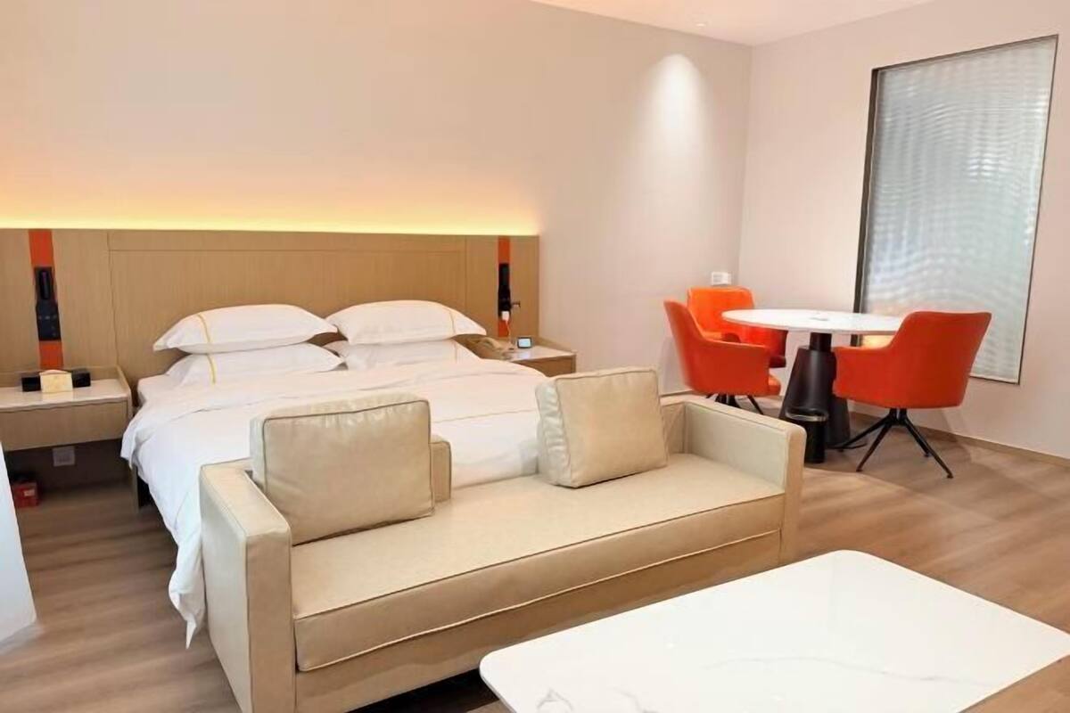A hotel room with a bed, a sofa, a table, and two chairs.