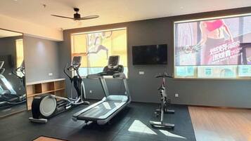 A gym with treadmills, stationary bikes, and a large screen displaying exercise content.