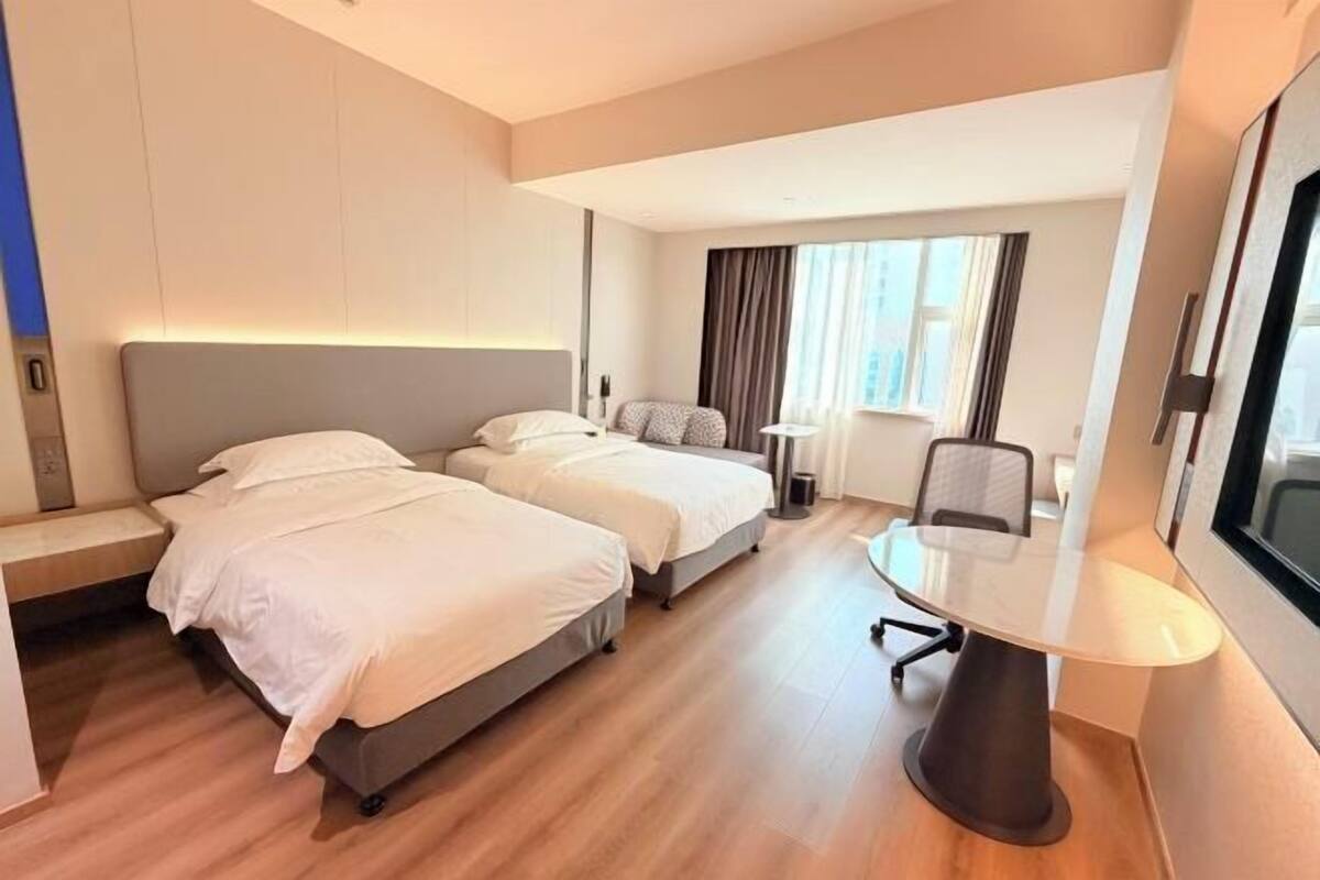 A hotel room with two beds, a desk, and a chair.