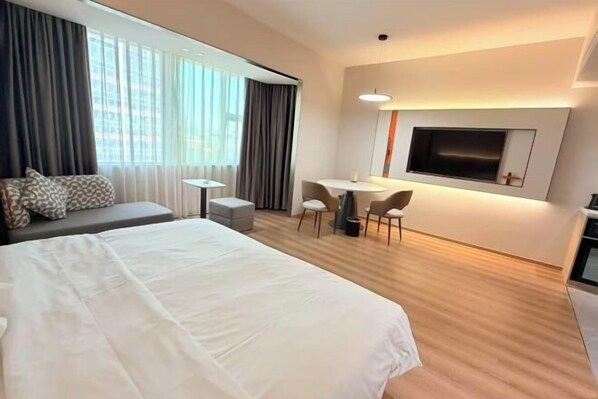 A hotel room with a large bed, a desk, and a TV mounted on the wall.