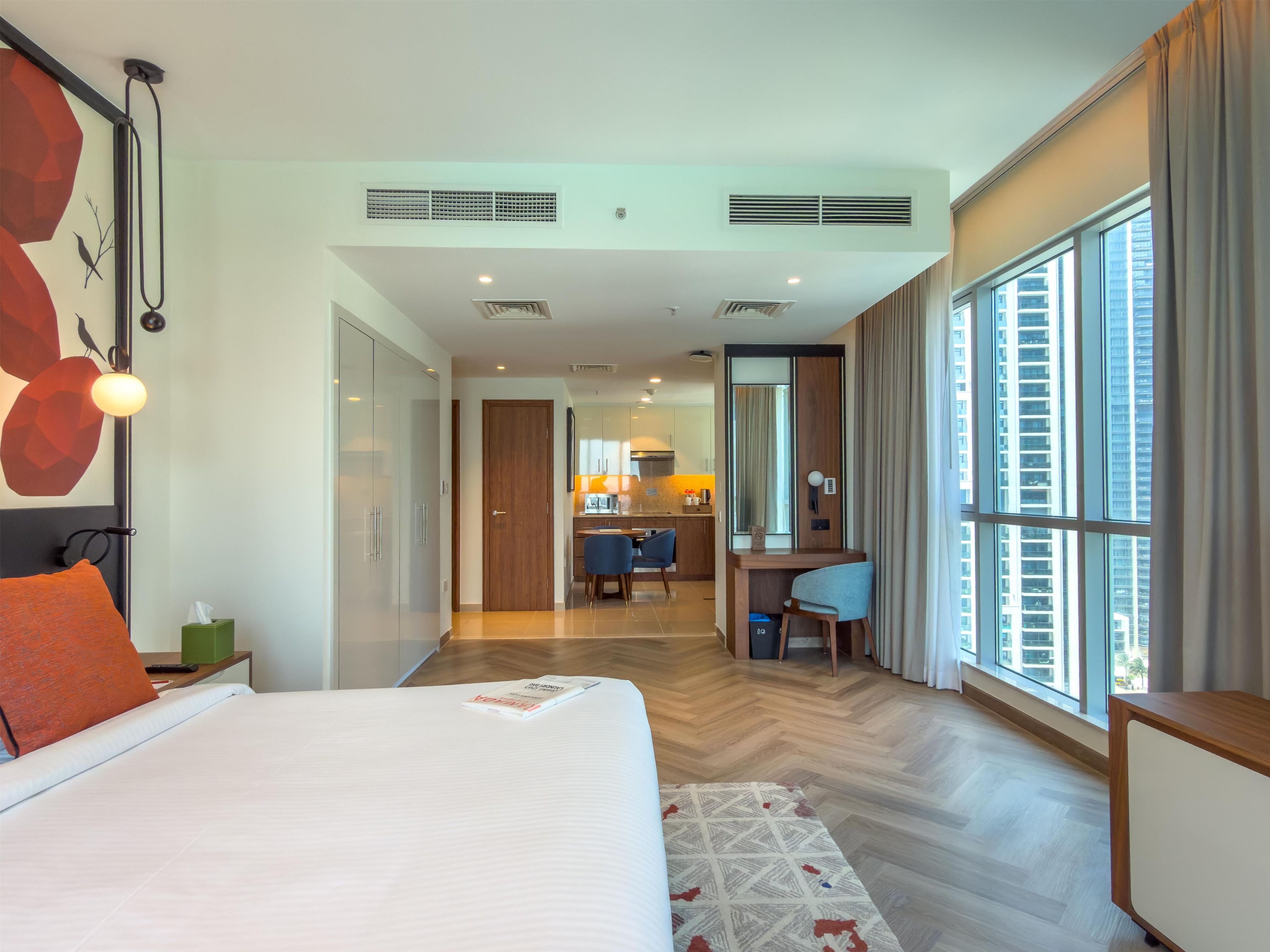 Ein modernes Hotelzimmer mit einem großen Bett, einem Schreibtisch und Blick auf die Stadt.