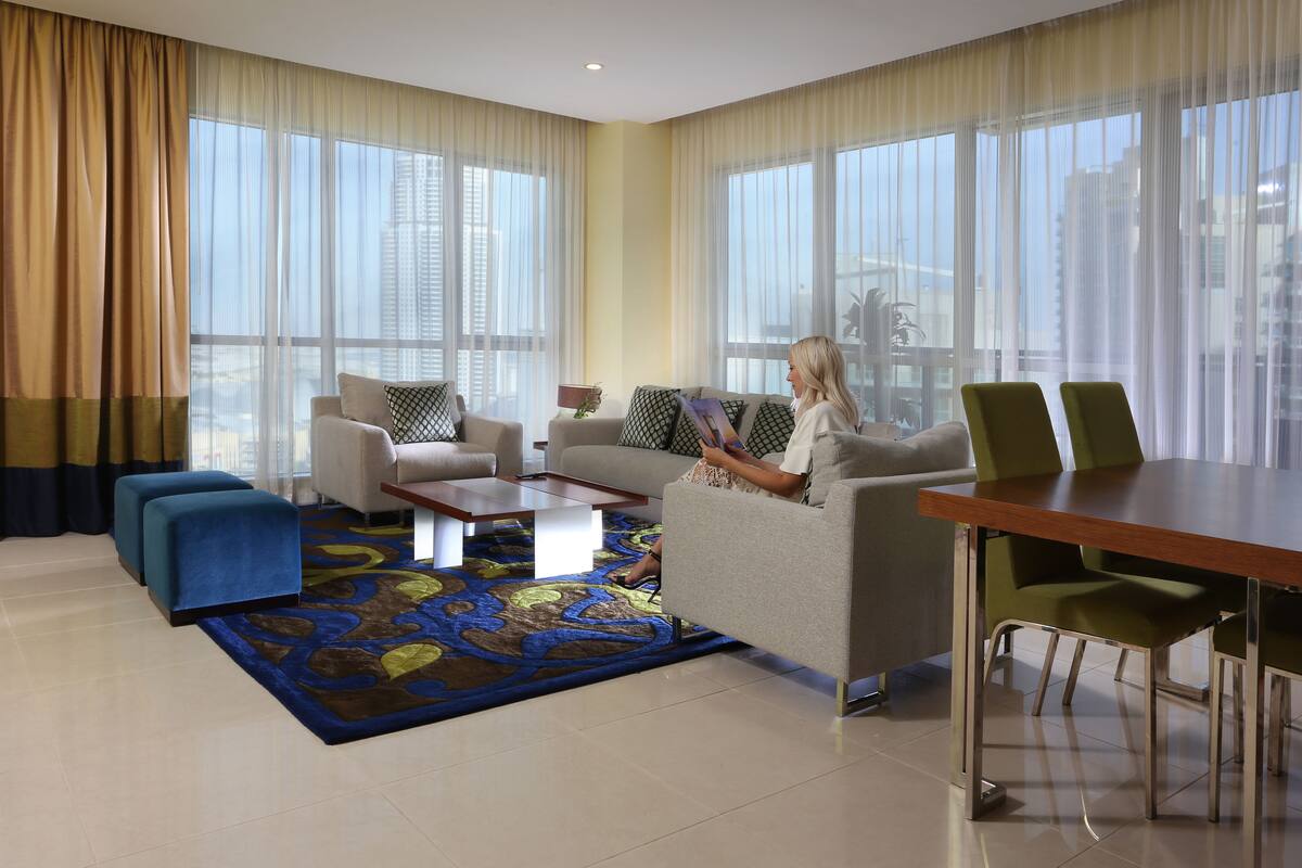Een moderne hotelkamer met een bank, fauteuils, een bijzettafeltje en een eethoek.