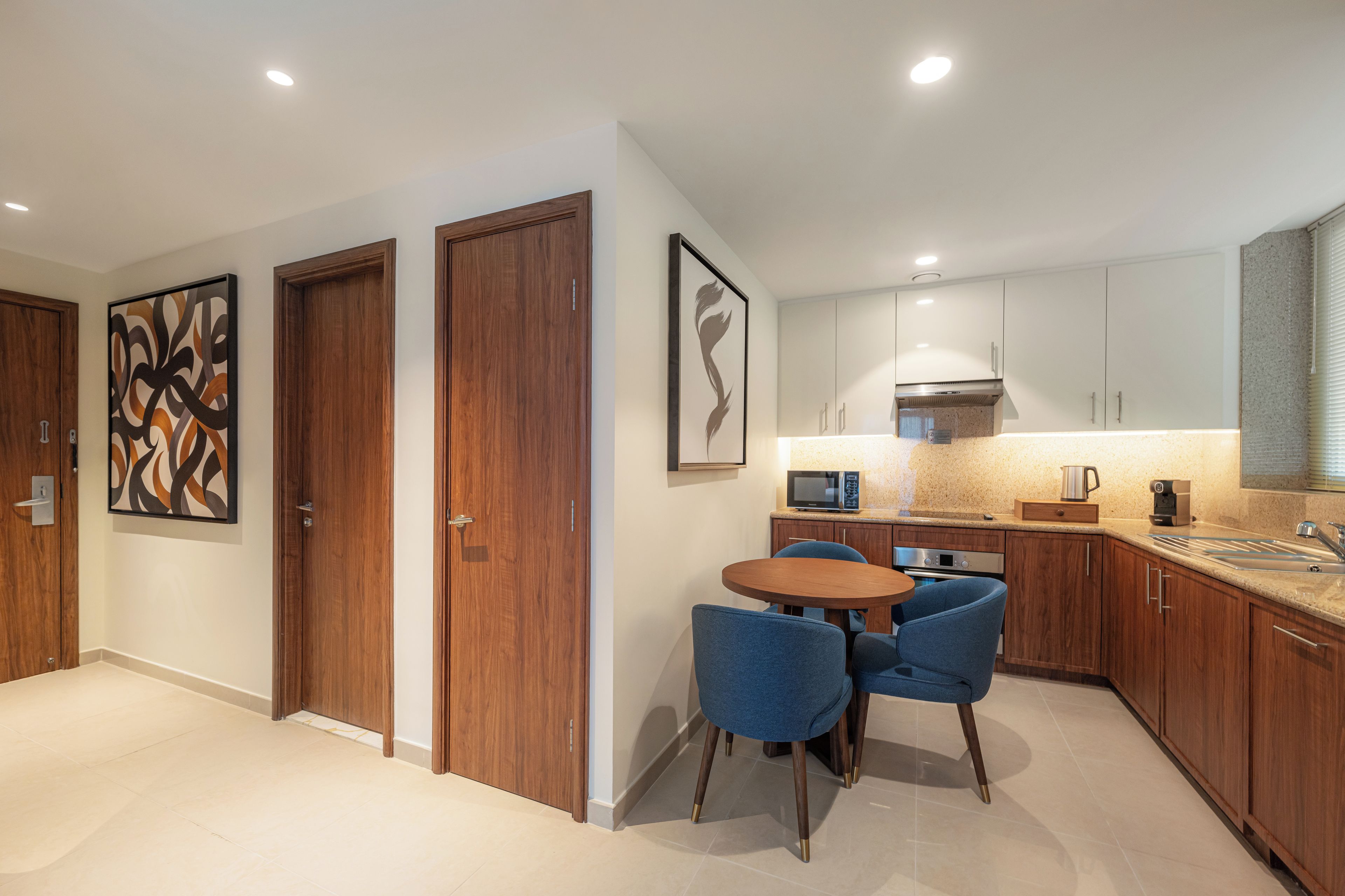 A modern kitchen with wooden cabinets, a dining table with chairs, and a microwave.