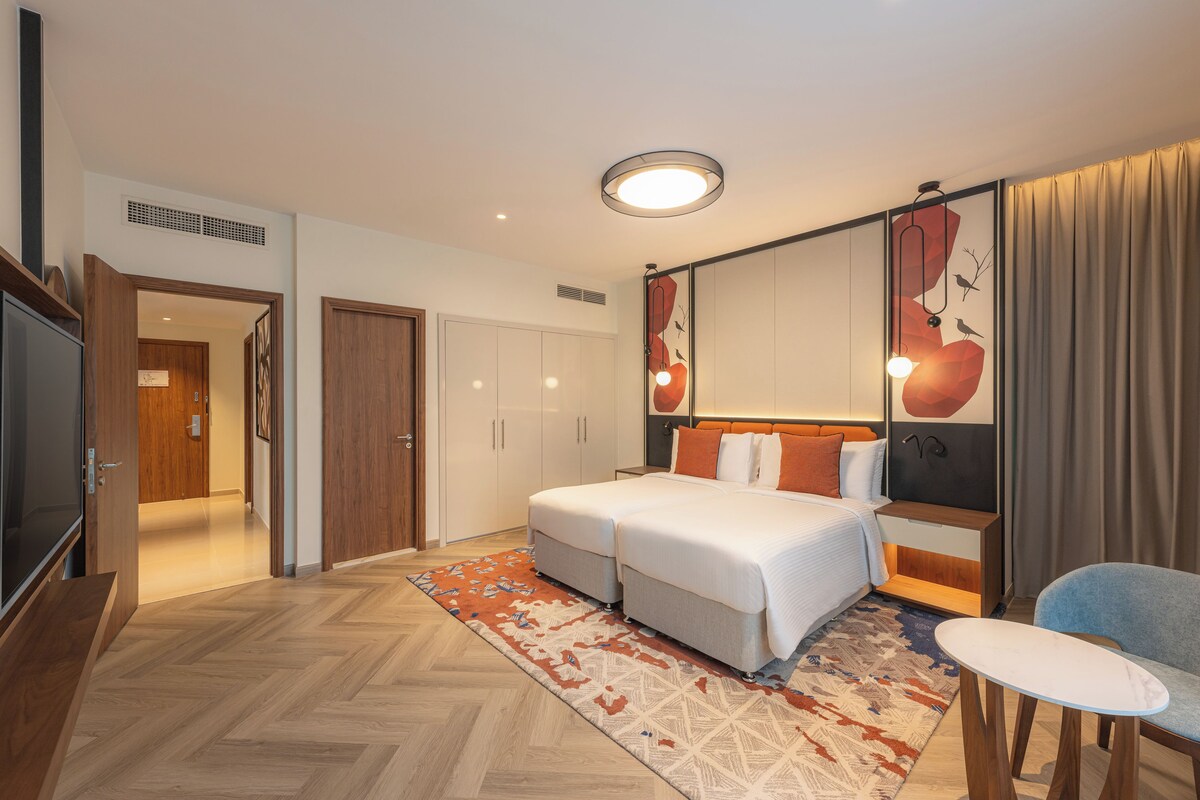 Een hotelkamer met een bed, een bureau, een stoel, een televisie en een grote spiegel.