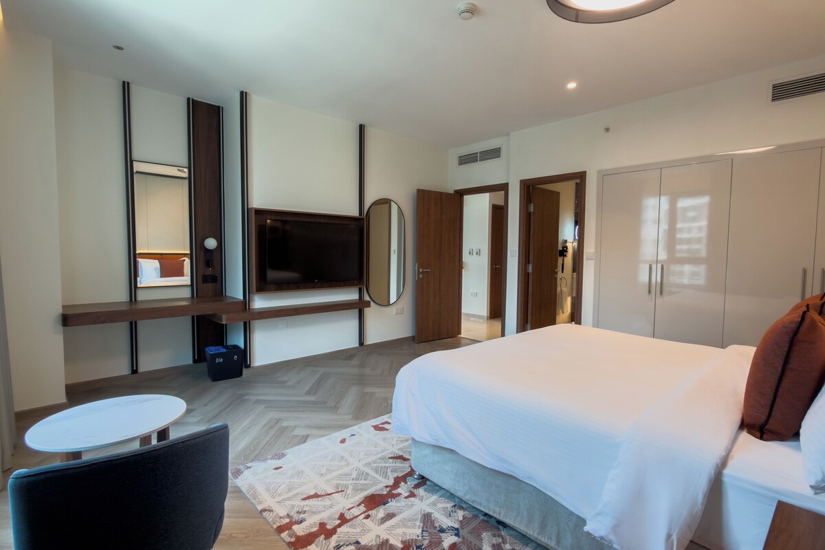 Een moderne hotelkamer met een bed, een televisie, een bureau en een kledingkast.