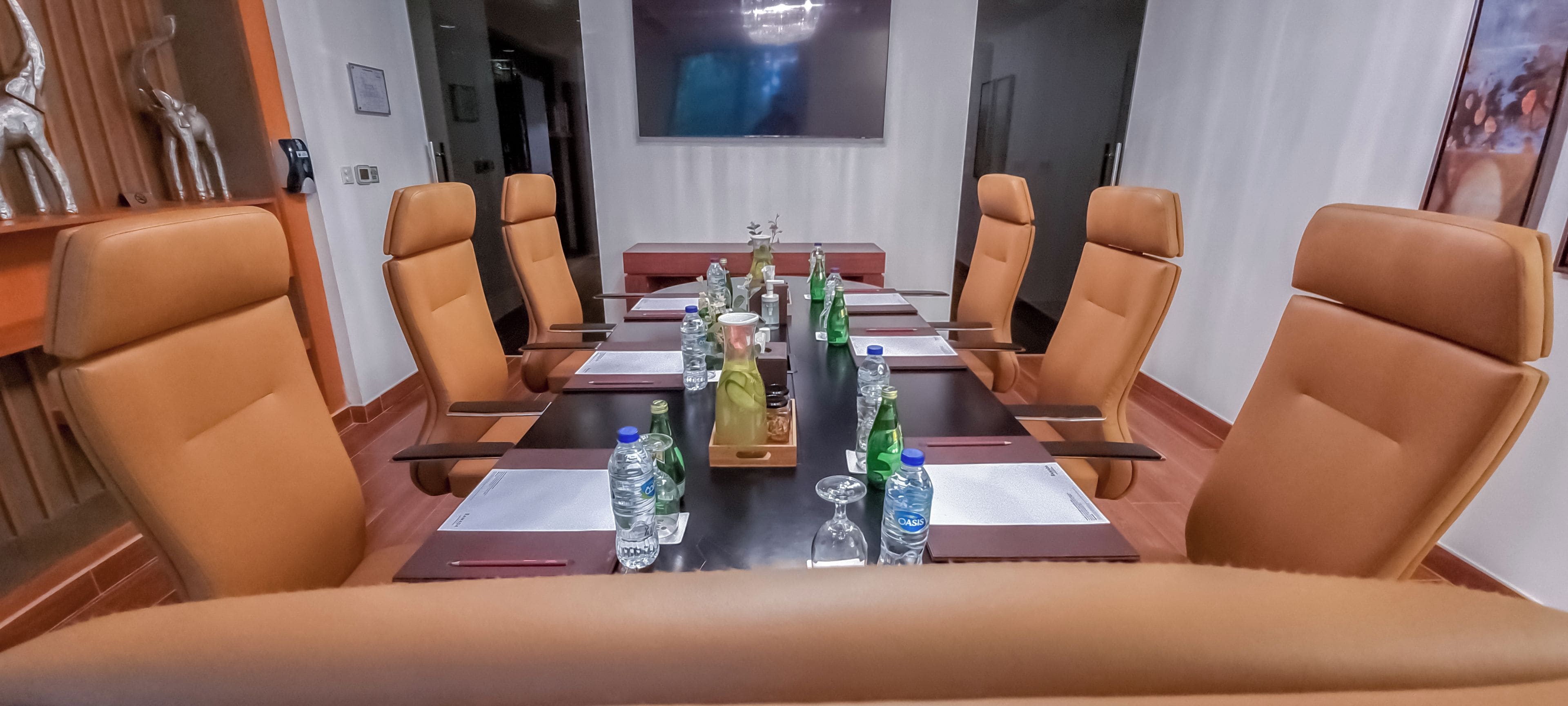 A conference room with a long table, brown leather chairs, and water bottles.