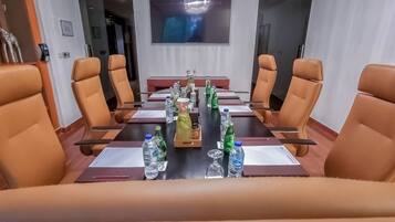 A conference room with a long table, brown leather chairs, and water bottles.