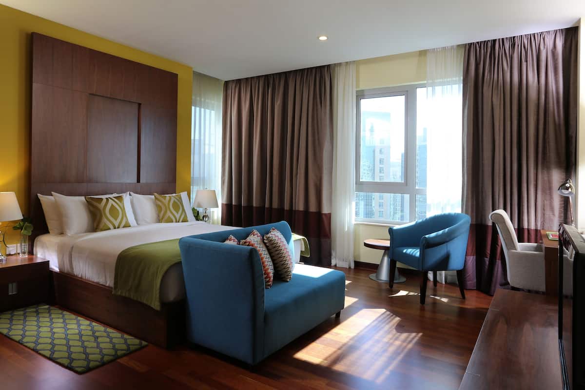 Een hotelkamer met een groot bed, een blauwe bank, een bureau en een stoel.