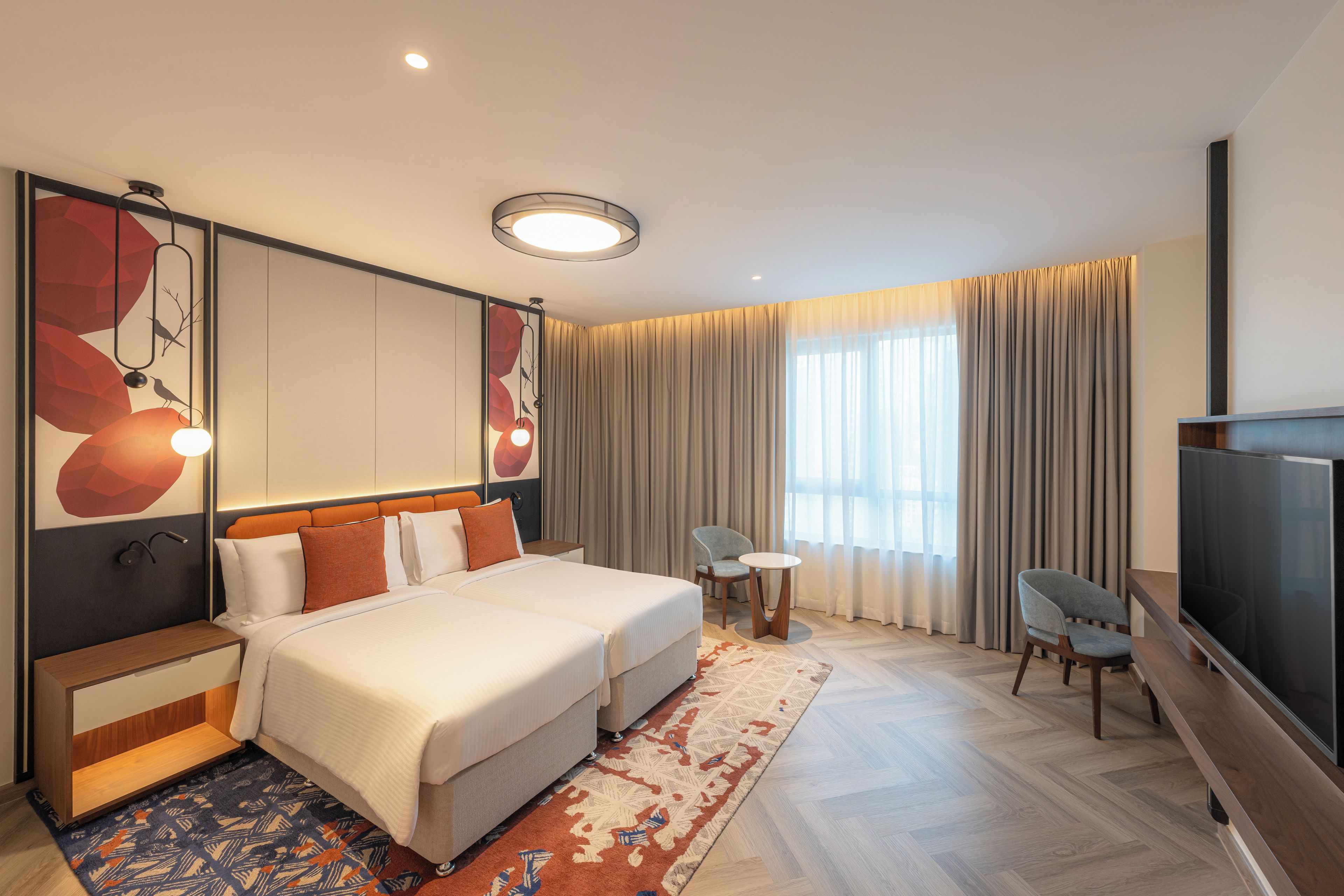 Ein Hotelzimmer mit einem großen Bett, einem Fernseher, einem Schreibtisch und einem Sessel.