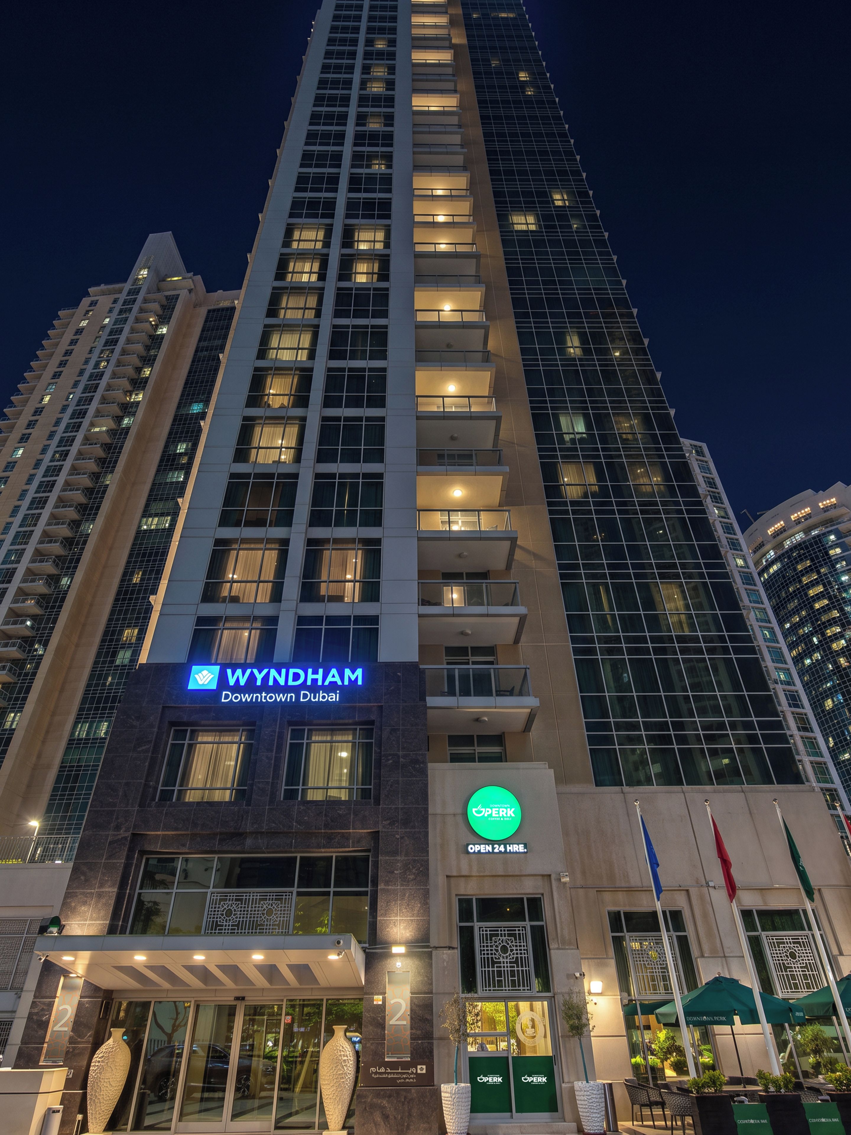 A high-rise building with a sign for Wyndham Downtown Dubai, a 24-hour coffee shop, and a number 2 entrance.