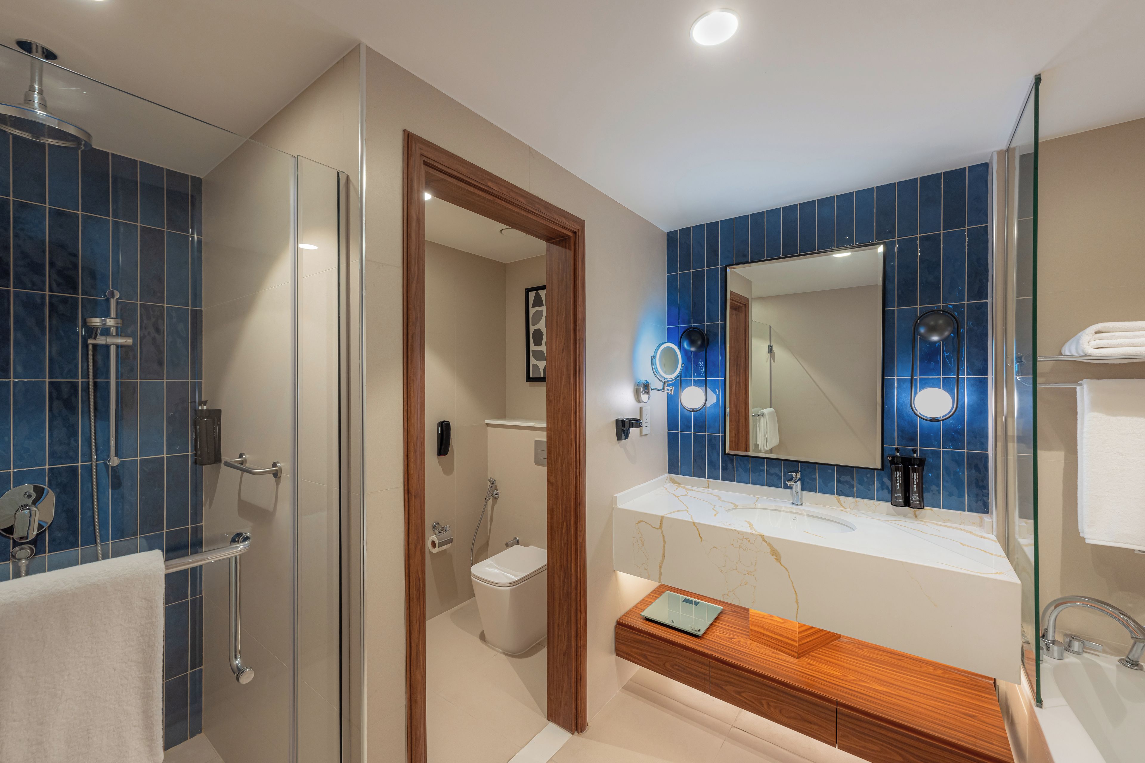 A modern bathroom with a glass shower enclosure, a wooden vanity, and a large mirror.