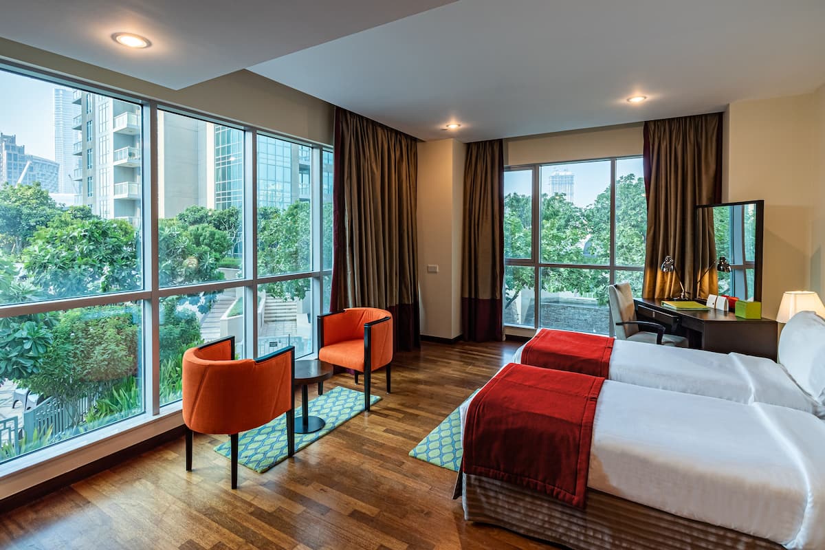 Een hotelkamer met grote ramen, een bed, een bureau en een stoel.