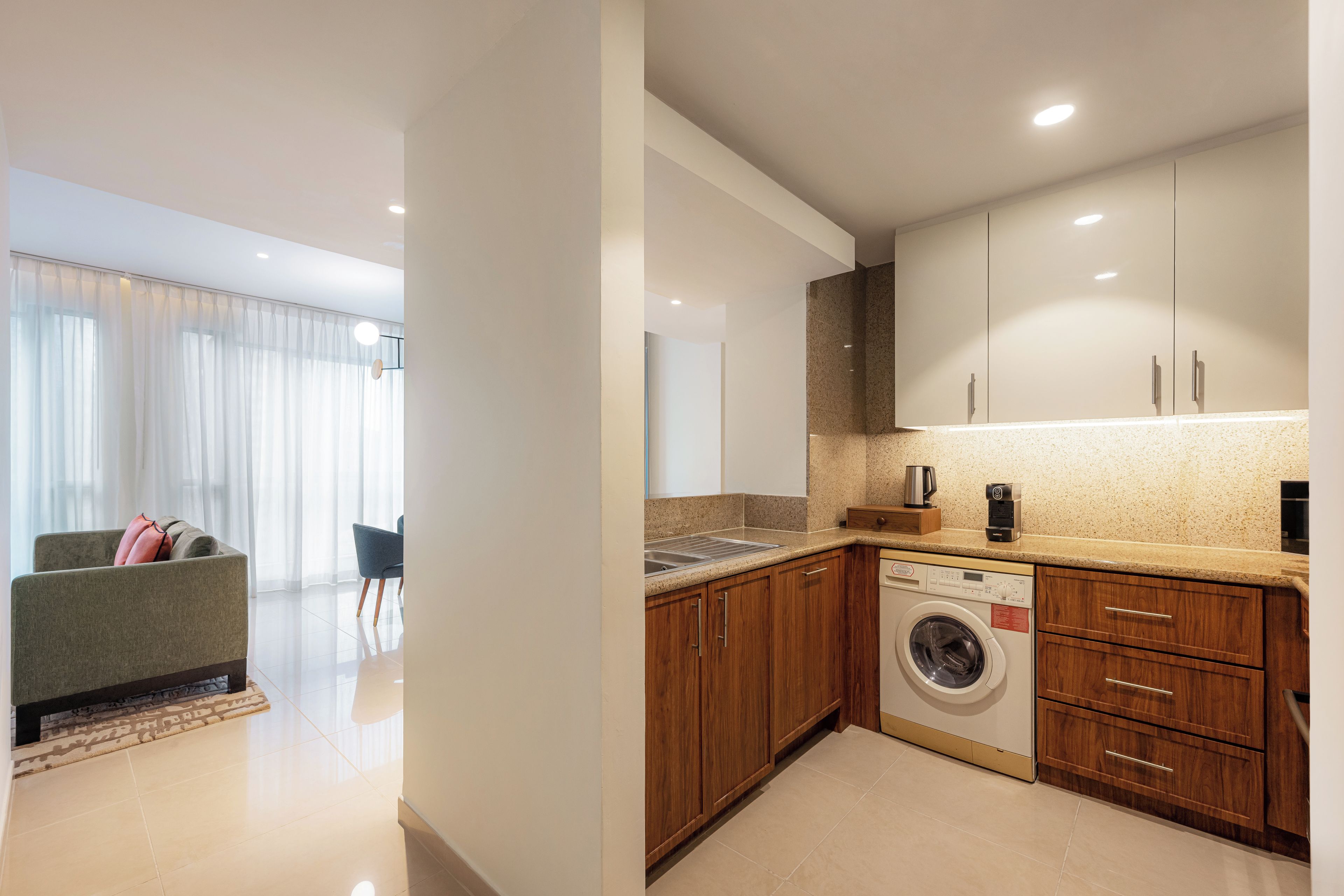 A modern kitchen with wooden cabinets, a built-in dishwasher, and a coffee machine.