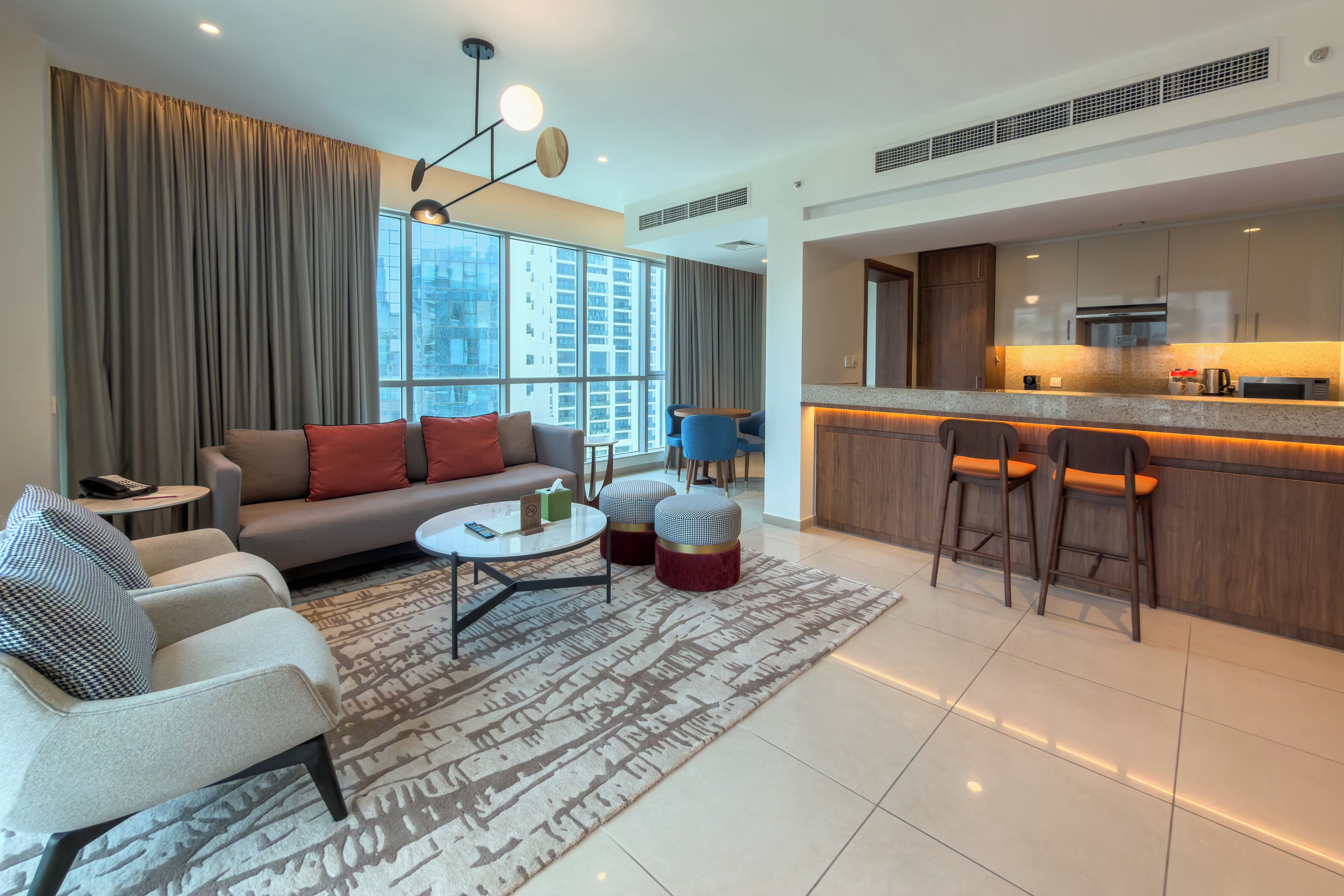 Una sala moderna con sofá, sillones, una mesa de centro y un tapete estampado.