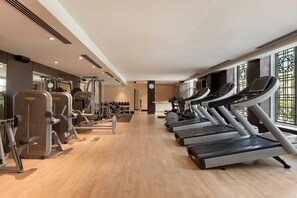 Een fitnessruimte met loopbanden, krachtapparaten en gewichten.