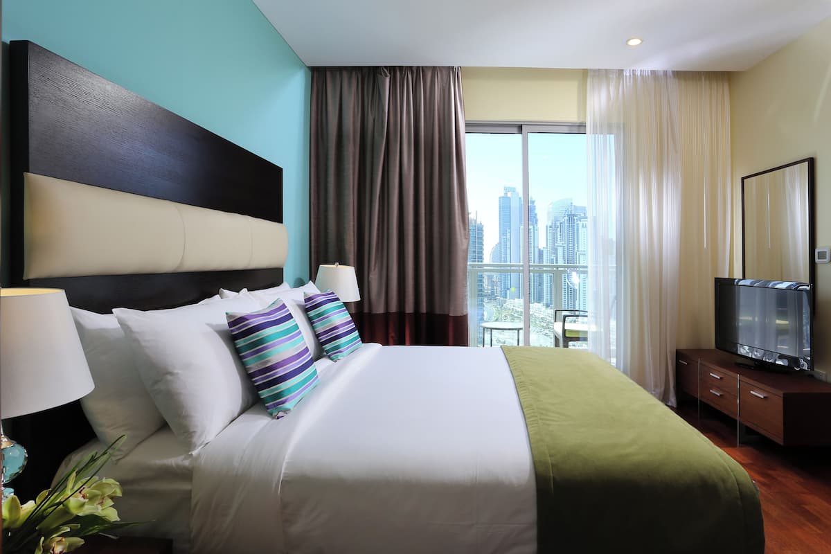 Een hotelkamer met een groot bed, een televisie en uitzicht op de stad.