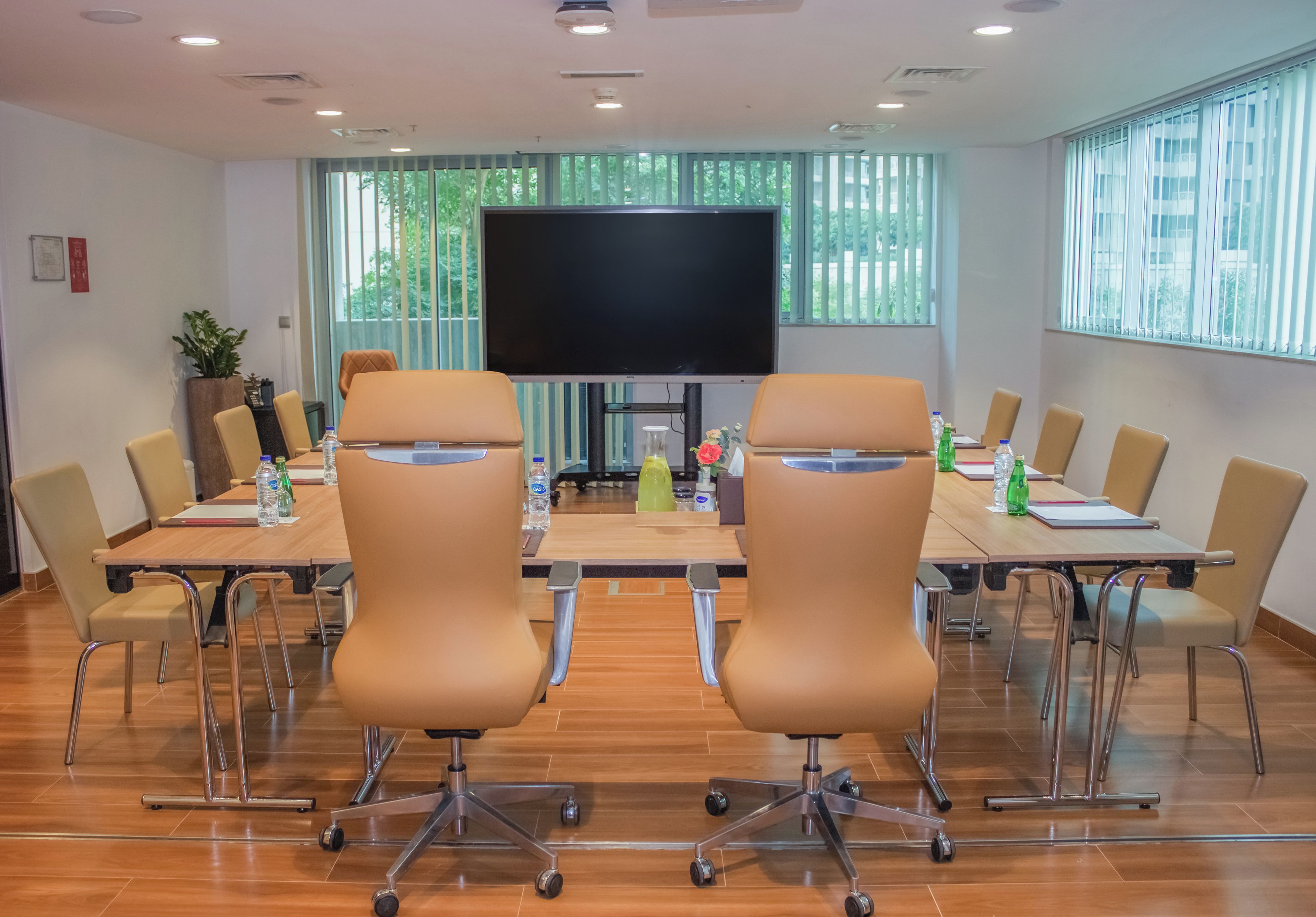 A conference room with a large flat-screen TV, a long table, and several chairs.