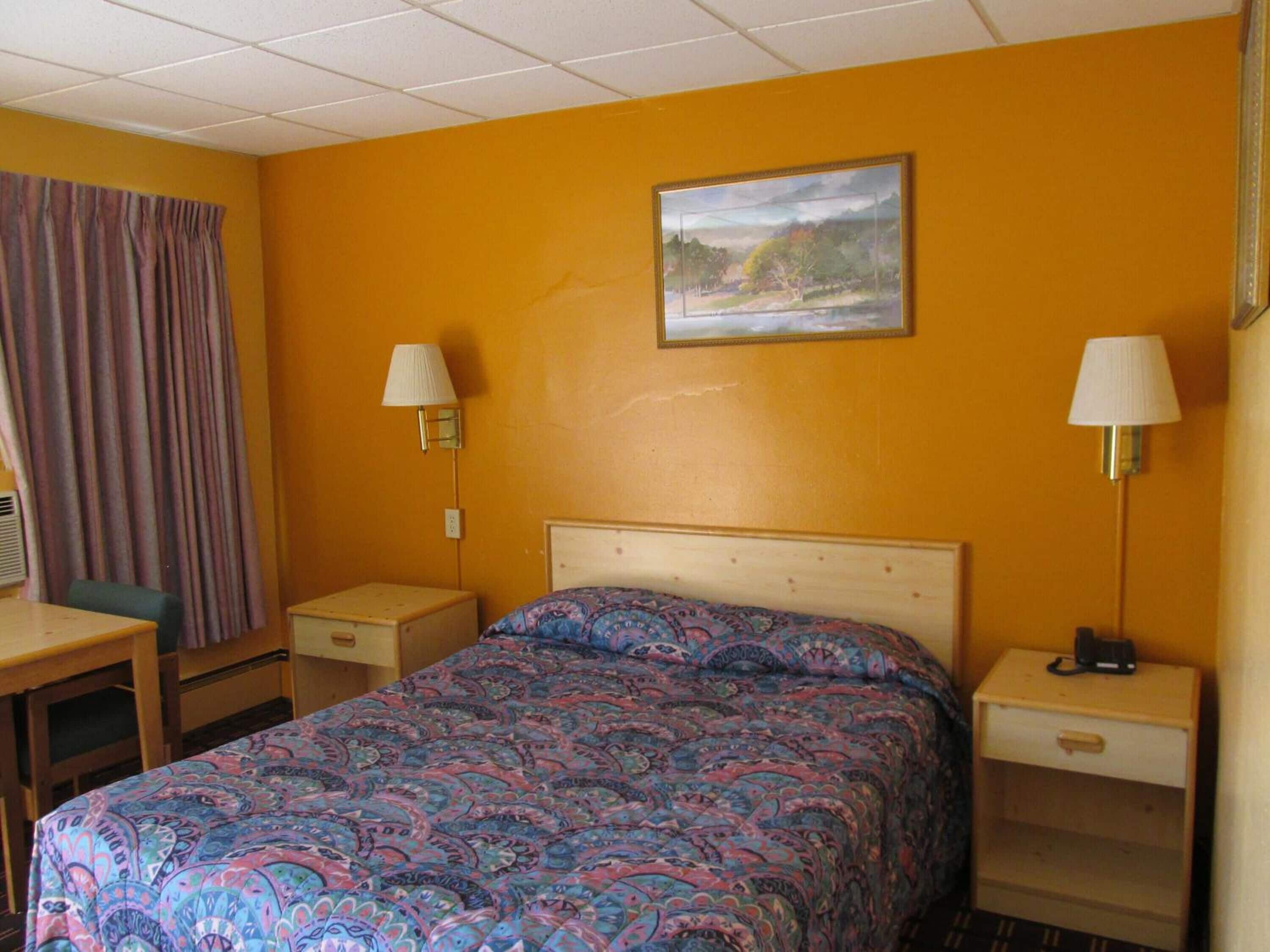 Een hotelkamer met een bed, twee nachtkastjes, een bureau en een stoel.