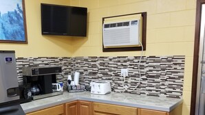 A small kitchen with wooden cabinets, a coffee maker, a toaster, and a microwave. - Motel 7 Rawlins (Rawlins)