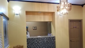 A hotel room with a wooden dining table, a small mirror, a chandelier, and a door marked "Employees Only". - Motel 7 Rawlins (Rawlins)