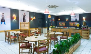 A restaurant with wooden chairs and tables, a counter with a display of fruits, and hanging pendant lights. - ibis Uberlandia (Uberlandia)