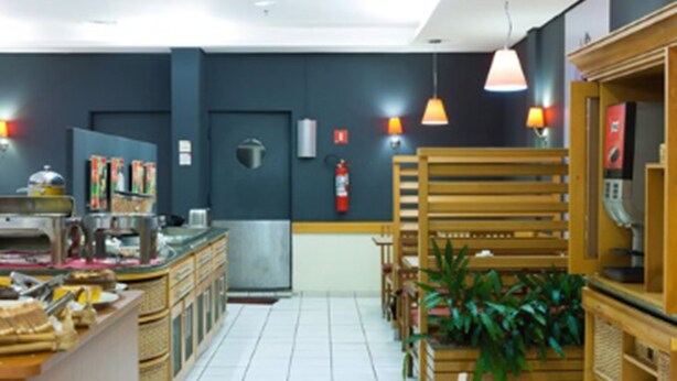 A restaurant with a counter, chairs, tables, and hanging pendant lights. - ibis Uberlandia (Uberlandia)