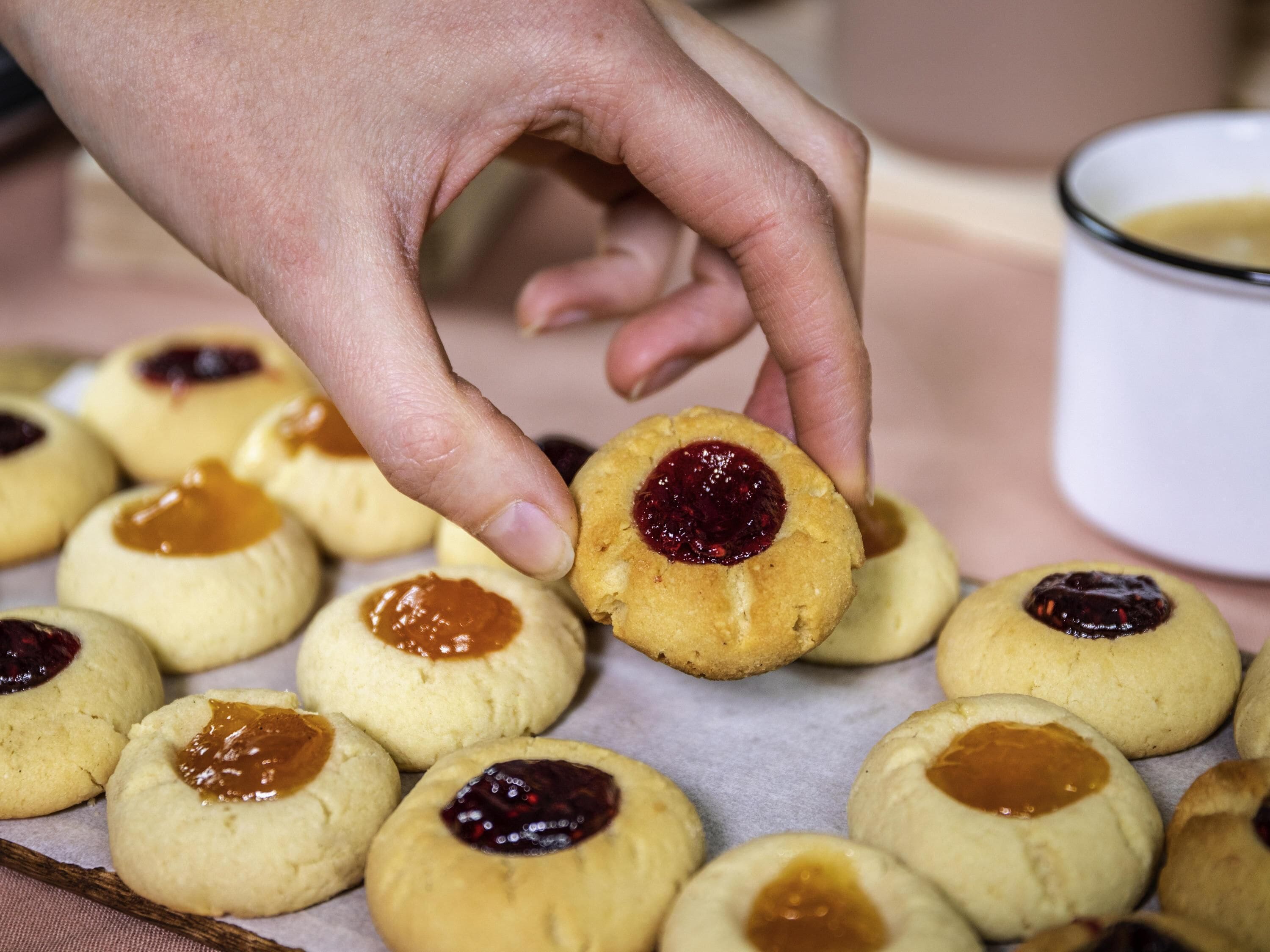 Een hand pakt een koekje met jamvulling.