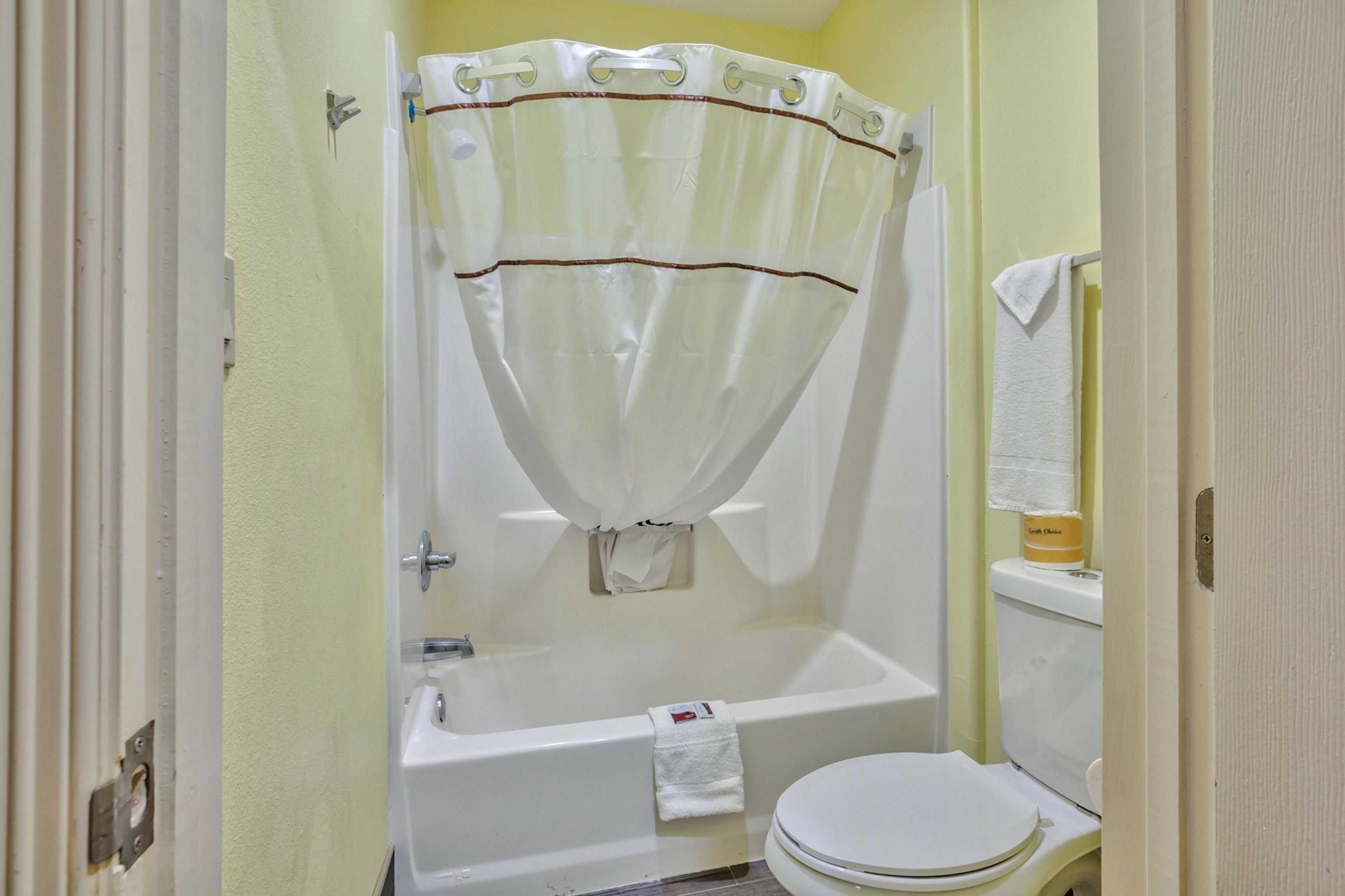 Une salle de bain avec une baignoire, des toilettes et un rideau de douche.