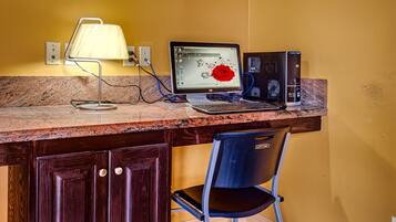 Ein Arbeitsplatz mit Schreibtisch, Laptop, Desktop-Computer, Lampe und Stuhl.