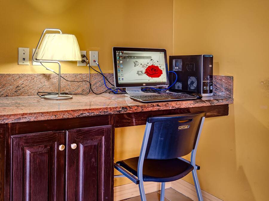 Ein Arbeitsplatz mit Schreibtisch, Laptop, Desktop-Computer, Lampe und Stuhl.