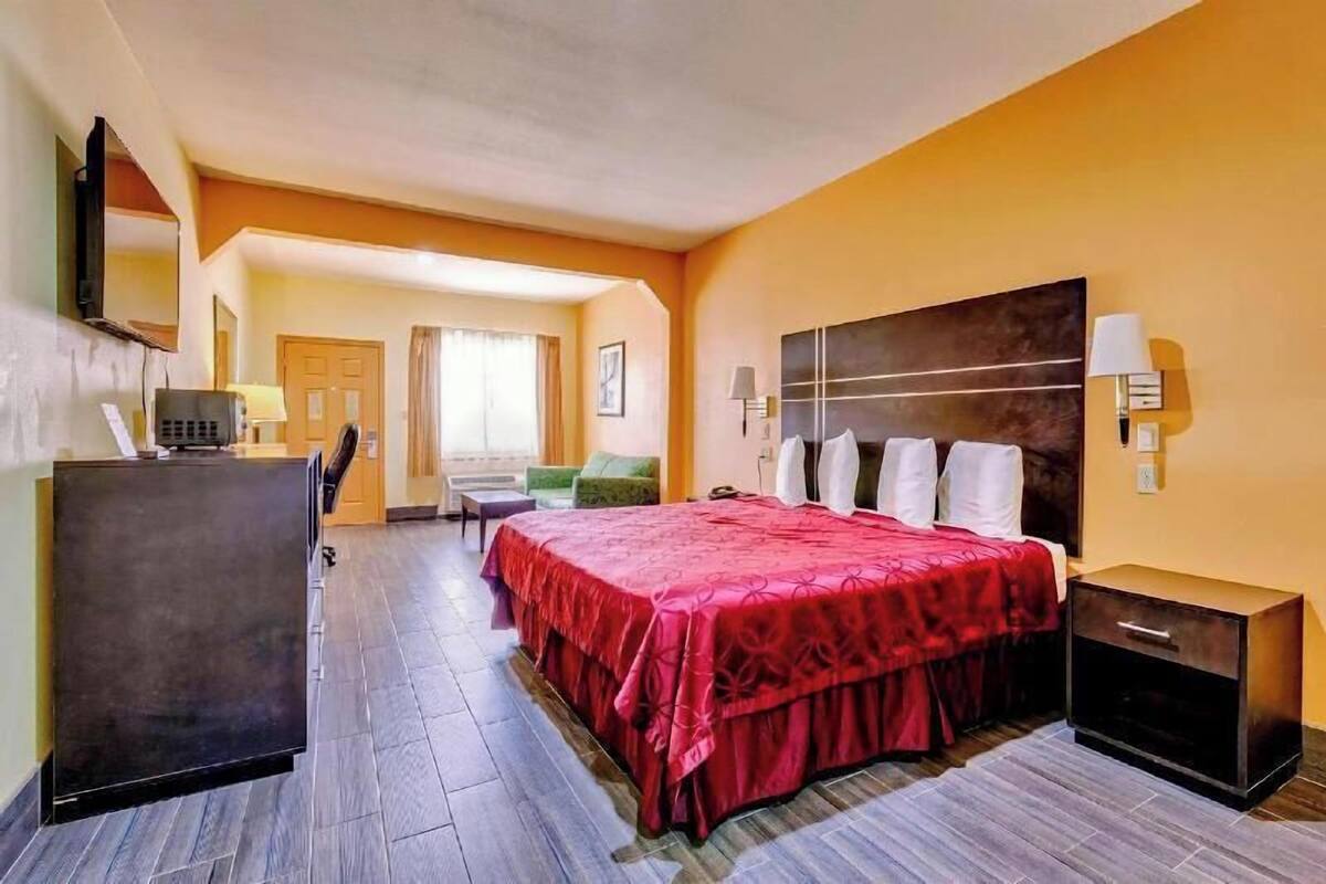 Une chambre d’hôtel équipée d’un lit, d’une table de chevet, d’une lampe et d’un bureau avec un ordinateur.