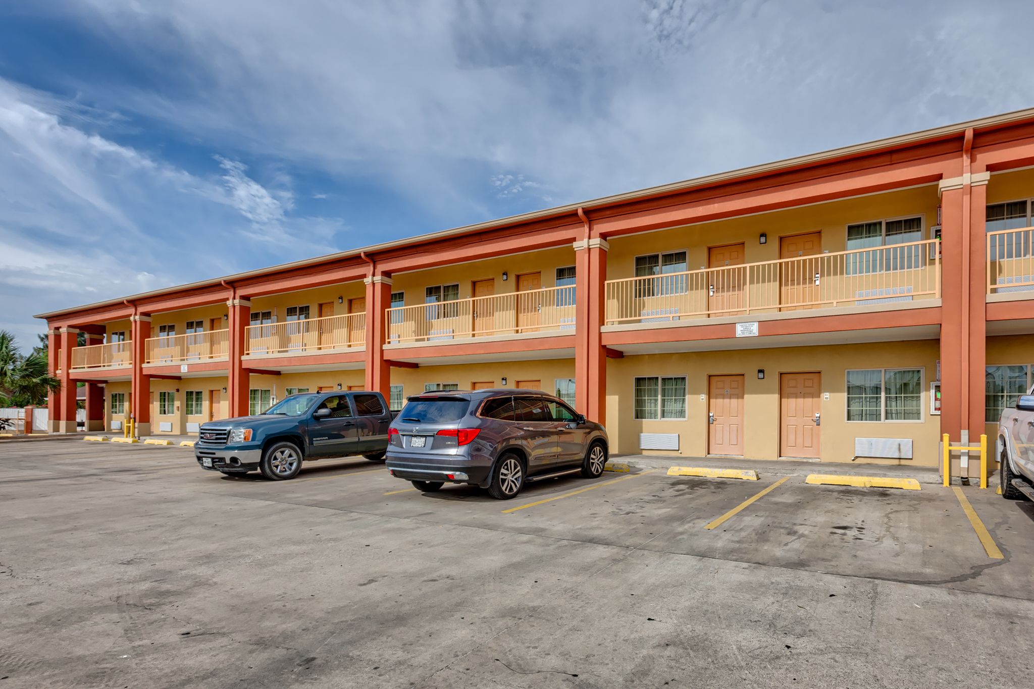 A motel with multiple floors, a parking lot, and a clear sky.