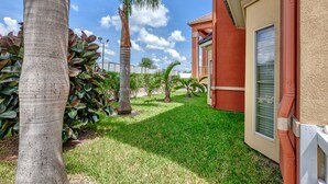 A residential area with a well-maintained lawn, palm trees, and a house with a red exterior and a window with shutters. - Quality Inn Brownsville (Brownsville)