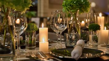 A table set with wine glasses, candles, and greenery.