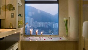 A bathroom with a bathtub, candles, and a city view. - Crowne Plaza Hong Kong Causeway Bay by IHG (Hong Kong)